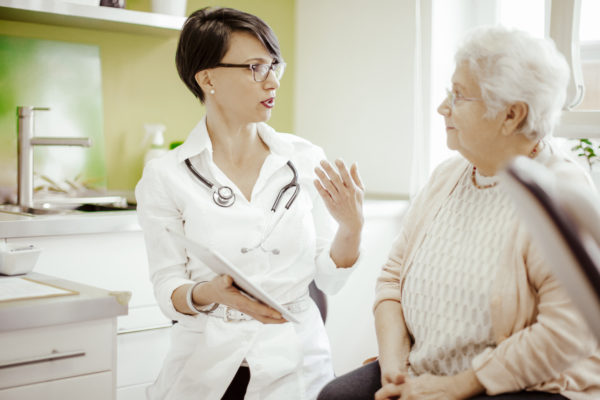Female doctor consulting with elderly female patient